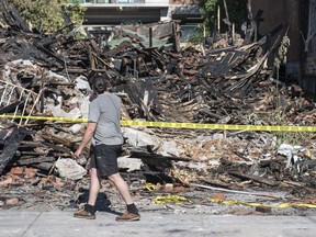 Pedestrians walk past damage to a house on Lebreton St. N that was destroyed by a suspicious fire early Tuesday, September 6, 2016. The Annunciation Orthodox Church sustained $250,000 in damage after flames spread to it.
