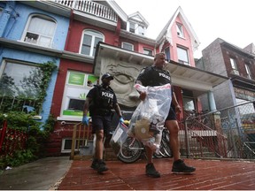 Toronto police officers  carry out bags of cannabis products during a raid on a marijuana dispensary last May. Ottawa police are now pondering what to do about the illegal pot shops here.