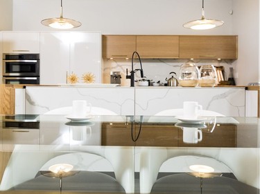 Eating area: An amoeba-shaped plaster bulkhead is suspended about two inches from the ceiling above the kitchen table. Backlit with LED lighting ‘you get this really nice spilling of light across the ceiling,’ says designer Donna Correy. In an example of the modern retro esthetic of the home, a glass-topped table is supported by a chunky distressed wood frame and black-and-white chairs reminiscent of the 1960s. The light fixture (Aura Pendant by Hubbardton Forge, available through Living Lighting) adds an industrial edge.
