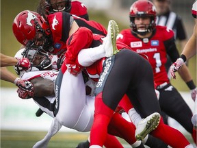 The Ottawa Redblacks' Tristan Jackson, left, is tackled by Calgary Stampeders players during the first half in Calgary on Saturday, Sept. 17, 2016.