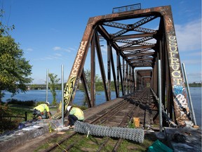 Workers install fencing around the derelict and closed Prince of Wales Bridge over the Ottawa River.  The cities of Ottawa and Gatineau felt access to the bridge needed to be better restricted.