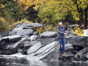 A man spends his drizzly morning fishing at the bottom of Hog's Back Falls Sunday October 16, 2016.    Ashley Fraser / Postmedia