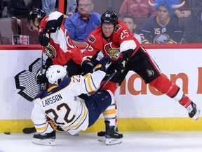 The Buffalo Sabres' John Larsson, middle, gets slammed to the ice by the Ottawa Senators' Chris Neil as teammate Erik Karlsson stays on the puck at the Canadian Tire Centre on Friday, Oct. 7, 2016.
