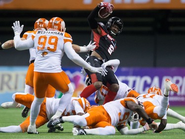 Ottawa Redblacks' Ernest Jackson, centre, is tackled by B.C. Lions' Loucheiz Purifoy, back, during the first half of a CFL football game in Vancouver, B.C., on Saturday October 1, 2016.