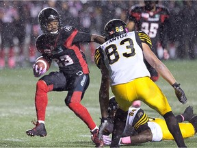 The Redblacks' Forrest Hightower, left, avoids a tackle after intercepting a pass during the first half against the Tiger-Cats at TD Place stadium on Friday, Oct. 21, 2016.