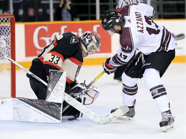 Gee Gee forward Marco Azzano, right, tries to dig at the puck between Ravens goalie Francois Brassard's pads in the second period.