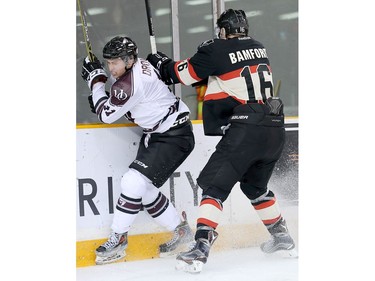 Gee Gee winger Cody Drover, left, is checked into the boards by Ravens forward Sean Bamford in the second period.
