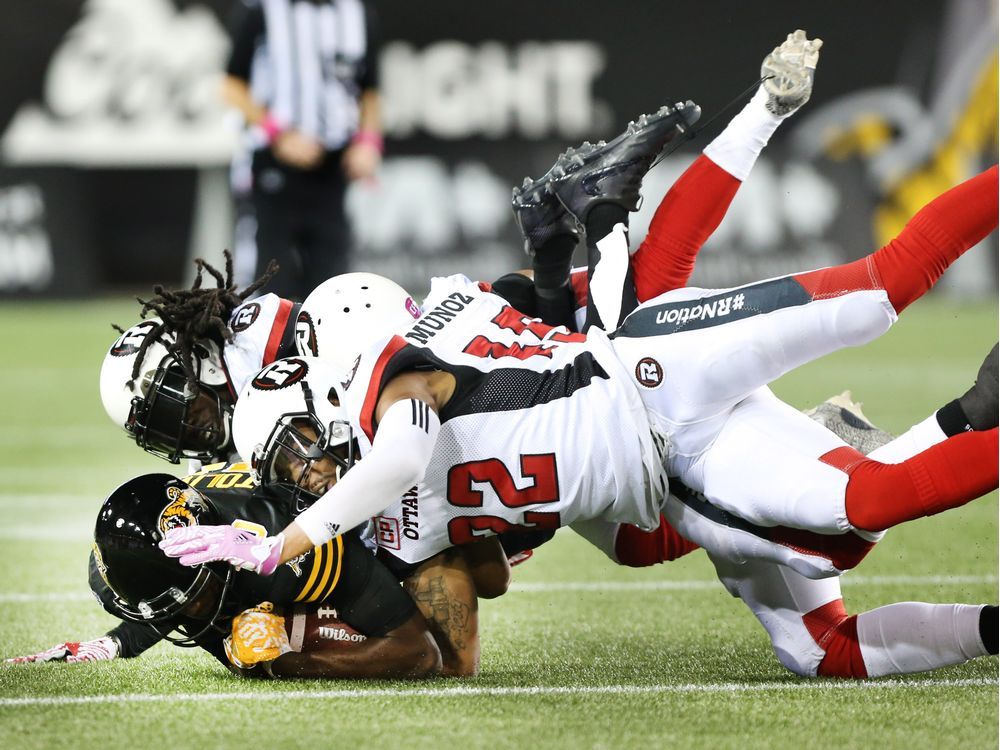 The Hamilton Tiger-Cats' Terrence Toliver is tackled by three Ottawa Redblacks.