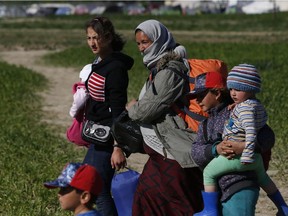 Iraqi Yazidi people carrying their belongings leave Idomeni camp, Greece, and head towards another camp near the town of Katerini in Greece, Tuesday, April 12, 2016.