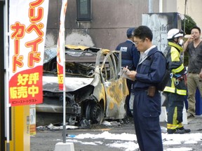 Policemen and firefighters investigate a parking lot after an explosion in Utsunomiya, some 100 kilometres (60 miles) north of Tokyo, on October 23, 2016. One person was killed and at least two injured by two near-simultaneous blasts in a Japanese park on October 23, the local fire department said. /