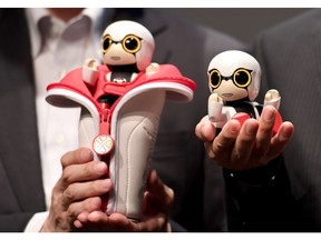 This picture taken on September 27, 2016 shows Toyota Motors new concept planning department project general manager Fuminori Kataoka (L) and president of the mid-size vehicle company and the senior managing officer of Toyota Motors Moritaka Yoshida (R) displaying the company's new communication robot 'Kirobo Mini' during a press preview in Tokyo. Equipped with artificial intelligence and a built-in camera, the robot is capable of recognising the face of the person speaking to him and responding in unscripted conversation or even starting a chat. /
