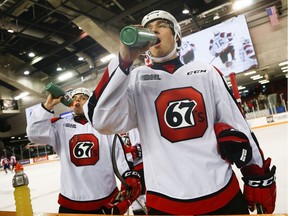 Ottawa 67's players Chase Campbell, left, and Peter Stratis quench their thirst during the warmup before a game against the Saginaw Spirit at TD Place arena on Saturday, Oct. 8, 2016.