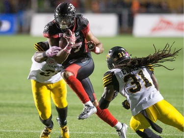 Mossis Madu Jr. of the Redblacks is tackled by Dominique Ellis and Simoni Lawrence (behind) of Hamilton during the first half on Friday, Oct. 21, 2016 at TD Place stadium.