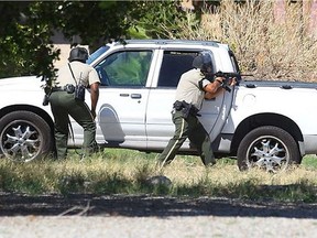 Officers take cover behind a pickup truck after gunshots were fired in Palm Springs, Calif., on Saturday, Oct. 8, 2016.