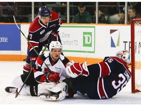 The Ottawa 67's Ben Fanjoy crashes in front of Saginaw Spirit goalie Evan Cormier, with Mitchell Stephens looking on.