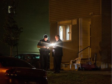 Police check their notes at the scene of an apparent homicide outside of 1411 Rosenthal Ave off of Merivale Rd in the Carlington neighbourhood.   Wayne Cuddington/ Postmedia