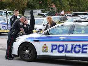 Police investigators interview witnesses at the scene of a double stabbing on Geaorge Street near the Salvation Army.  Wayne Cuddington/ Postmedia