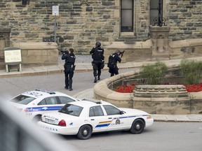 Police teams enter the Centre Block at Parliament Hill in Ottawa on Oct. 22, 2014 in pursuit of an attacker.