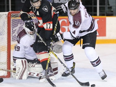 Ravens forward Ryan Van Stralen, centre, looks for the loose puck in front of Gee Gee goalie Graham Hunt with Gee Gee defenceman Jacob Sweeney guarding the net in the first period.