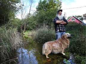 Bob Gregory and his dog Goose stand beside their creek outside their home in Dunrobin, Ontario.