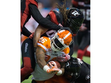 Ottawa Redblacks' Taylor Reed, top, and Damaso Munoz tackle B.C. Lions' Anthony Allen (26) during the first half of a CFL football game in Vancouver, B.C., on Saturday October 1, 2016.