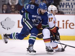 Vancouver Canucks defenceman Erik Gudbranson (44) fights for control of the puck with Calgary Flames centre Lance Bouma (17) during first period NHL action, in Vancouver on Saturday, Oct. 15, 2016.