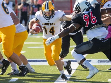 Windsor QB Casey Wright tries to avoid a tackle with Tevin Bowen (R) in pursuit as the Carleton Ravens take on the Windsor Lancers in OUA football action at MNP Park on the Carleton University campus.