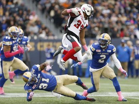 Ottawa Redblacks' Mossis Madu Jr. (37) leaps over Winnipeg Blue Bombers' Maurice Leggett (31)to avoid the tackle as Khalil Bass (2) tries to clean up during the first half of CFL action in Winnipeg Saturday, October 29, 2016.
