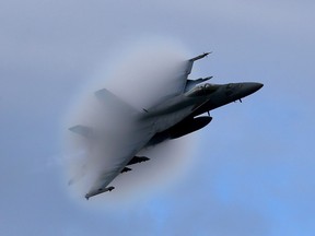 A F18 Super Hornet creates a vapor cone as it flies at a transonic speed while doing a flyby of the USS Eisenhower in the Atlantic Ocean off the coast of Virginia, Thursday, Dec. 10, 2015. The federal Liberal government says it will ``explore the acquisition'' of 18 new Boeing-made Super Hornet jets on an interim basis until it can decide on a permanent replacement for Canada's aging fleet of fighter planes.THE CANADIAN PRESS/AP-Mark Wilson/Pool Photo via AP ORG XMIT: CPT119