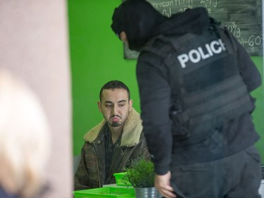 A man who went by the name "Curly" grimaces while being interrogated as Ottawa police conduct raids on a number of pot shops including Wee Medical on Rideau St. He later said he was released without charges as he was only a customer in the shop.