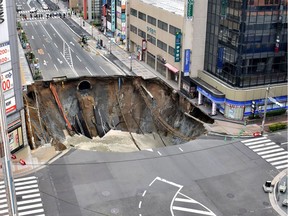A massive shinkhole is created in the middle of the business district in Fukuoka, southern Japan Tuesday, Nov. 8, 2016. Parts of a main street have collapsed in the city, creating a huge sinkhole and cutting off power, water and gas supplies to parts of the city. Authorities said no injuries were reported from Tuesday's pre-sunrise collapse in downtown Fukuoka. (Kyodo News via AP) ORG XMIT: TKMY803