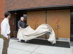 A painter lays down a tarp before painting the doors at the Congregation Machzikei Hadas at 2310 Virginia Dr. in late 2016. It was spray painted with swastikas and foul racial messages.