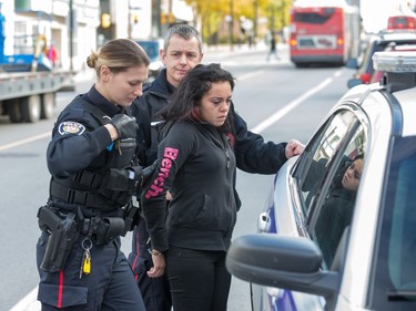 A woman is arrested and placed in a cruiser as Ottawa police conduct raids on a number of pot shops including Wee Medical on Rideau St.