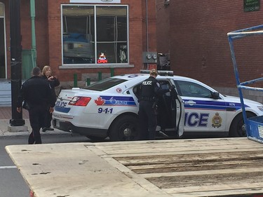 Police lead a person working at the marijuana dispensary out in handcuffs, taken away in police car.