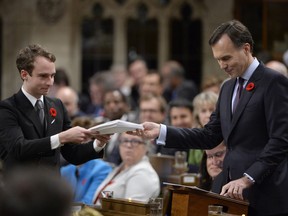 Finance Minister Bill Morneau gives a copy of the government's fall economic update to a page in the House of Commons on Parliament Hill in Ottawa on Tuesday, November 1, 2016. THE CANADIAN PRESS/Adrian Wyld ORG XMIT: AJW604