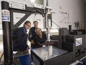 Engineers (L-R) Alanna Wall, Sean McTavish, and Richard Lee with the models of a helicopter and ship in the NRC wind tunnel where they are conducting research for DND.