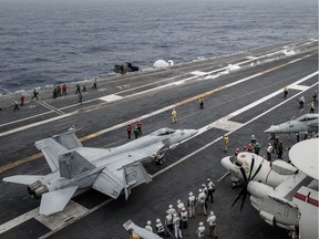 (FILES) This file photo taken on June 15, 2014 shows a US Navy Boeing F/A-18 Super Hornet multirole fighter jet (background)as it takes off as other F/A-18s, an E-2C Hawkeye airborne early warning aircraft (bottom R), and a C-2A Greyhound transport aircraft (top R) are pictured on the flight deck of the US nuclear-powered aircraft carrier USS George Washington off the coast of Hong Kong. Canada plans to order 18 Boeing F/A-18 Super Hornet fighter jets from Boeing and is seeking offers to update its aging combat fleet, Defense Minister Harjit Sajjan said on November 22, 2016. /