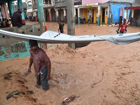 A man tries to clear debris from a partially flooded street during a seasonal storm on November 5, 2016 in the commune of Jeremie, southwestern Haiti, one of the cities hit hard by Hurricane Matthew.