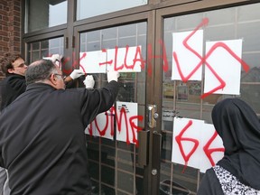 Hate graffiti on the Ottawa Mosque on Northwestern Ave being removed, Nov.18, 2016.