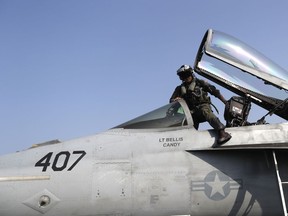 A fighter pilot climbs into the cockpit of F/A-18E Super Hornet jet before launching from the deck of the U.S.S. Dwight D. Eisenhower aircraft carrier towards targets in Iraq and Syria.