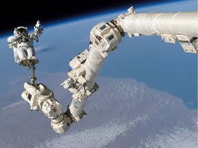 Astronaut Steve Robinson is shown clamped to the Canadarm2.