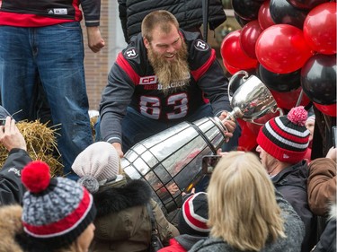 John Gott lets fans touch the cup during the parade as the Ottawa Redblacks celebrate their Grey Cup victory with a parade down Bank St and a celebration at Lansdowne Park.