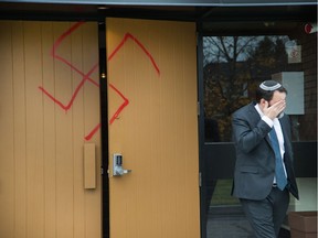 Joshua Dougherty wipes his eye as he comes through the doors at Congregation Machzikei Hadas at 2310 Virginia Dr which was spray painted with swastikas and foul racial messages sometime over the night.
