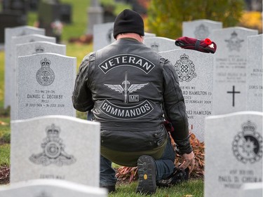 Ken Downton, a retired Warrant Officer who served as a parachute rigger, takes a moment at the grave site of his good friend Michael Hamilton who died in a training accident in 2009, as families, veterans, and military personnel attend Remembrance Day ceremonies at Beechwood Cemetery.