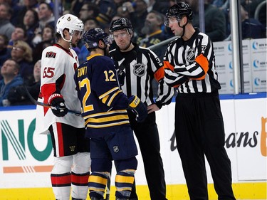 Brian Gionta #12 of the Buffalo Sabres and Erik Karlsson #65 of the Ottawa Senators talk with referee Eric Furlatt #27 and referee Kendrick Nicholson during the second period at the KeyBank Center on November 9, 2016 in Buffalo, New York.