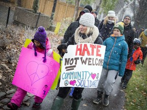 Residents gathered for a march against racism on Sunday, November 20, 2016, a day after a minor was charged for hate graffiti painted on several Ottawa buildings in the past week. L-R Six year old Arden Khan along with her mom Tabitha Bernard were wearing some community solidarity signs while taking part in the march on Sunday.