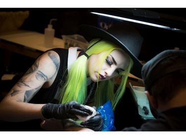 Gabrielle Munger from Addik Tattoo shop works on a client's tattoo on his arm during the Ottawa Gatineau Tattoo Expo at the Hilton Lac-Leamy on Saturday, Nov. 12, 2016. The expo runs through the weekend.
