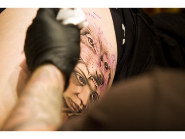 Jesse James of Planet Ink in Ottawa works on a woman's thigh tattoo Saturday afternoon at the Ottawa Gatineau Tattoo Expo at the Hilton Lac-Leamy. The expo runs through the weekend.