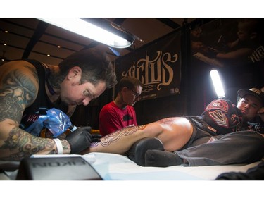 Maxine Gagmon braved two Gatineau tattoo artists — Roch Seguin, left, and Jean-Philippe Boudreau — working on a large leg piece at the same time.