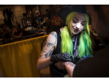 Gabrielle Munger from Addik Tattoo shop works on a client's tattoo on his arm during the Ottawa Gatineau Tattoo Expo at the Hilton Lac-Leamy on Saturday, Nov. 12, 2016. The expo runs through the weekend.